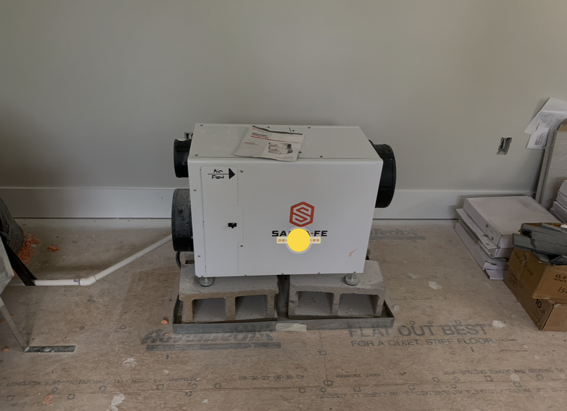 Santa Fe ducted dehumidifier installed on concrete blocks in an unfinished space with duct connections